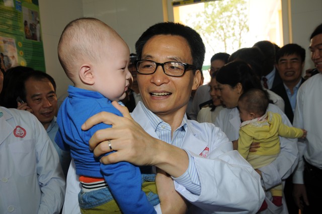 Phó Thủ tướng Vũ Đức Đam ân cần quan tâm em bé đi tiêm chủng tại trạm y tế xã Song Mai- Bắc Giang