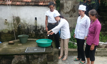 Cán bộ y tế đang hướng dẫn người dân cách xử lý nước sạch sau mưa bão
