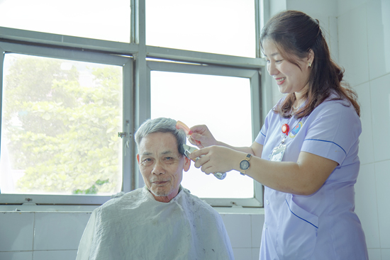 Điều dưỡng Bệnh viện đa khoa Hương Sơn cắt tóc cho bệnh nhân cao tuổi điều trị tại bệnh viện. Ảnh VT