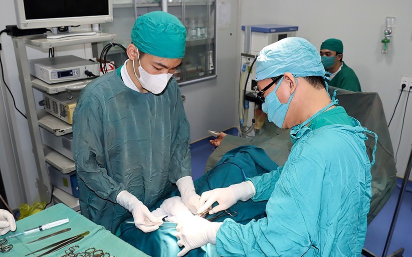 Bác sỹ Nhiệm (người bên phải) trực tiếp phẫu thuật nối gân bàn chân cho bệnh nhân.